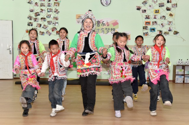 馬游小學(xué)社團(tuán)課上，梅葛文化國(guó)家級(jí)傳承人羅英老師教學(xué)生邊唱娃娃梅葛調(diào)邊跳彝族舞蹈。（蔡興華  攝影）.JPG